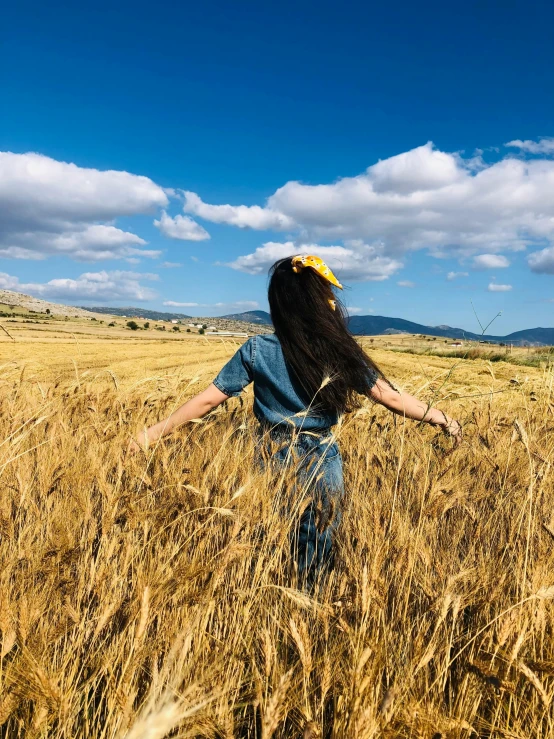 man with long hair in a field wearing cowboy hat