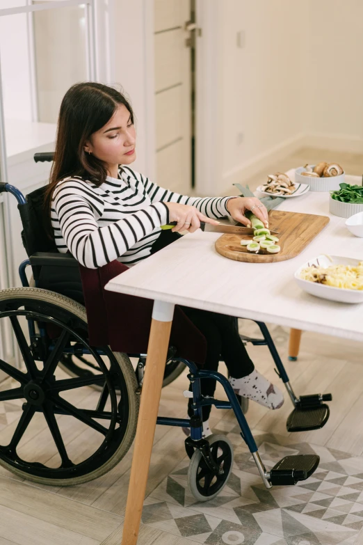 a woman in a wheel chair slices up food