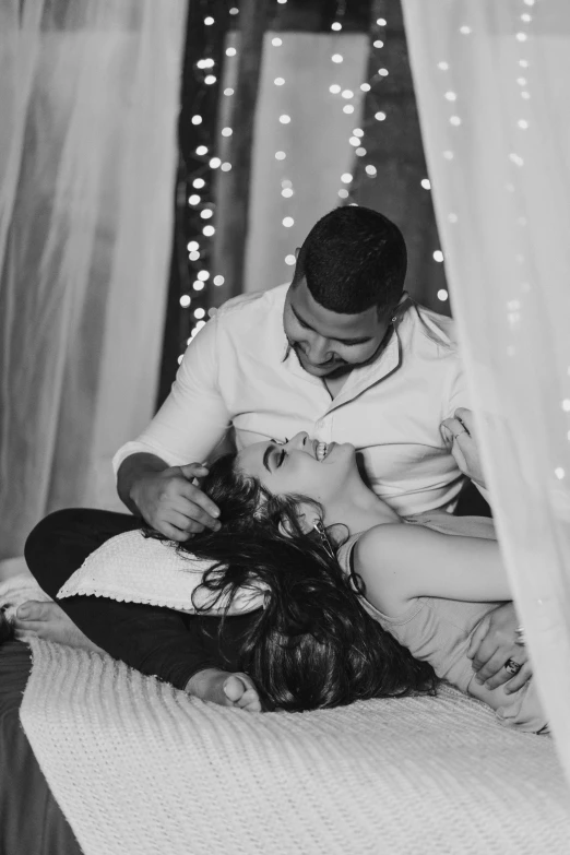 a young man hugs the back of a woman on a bed