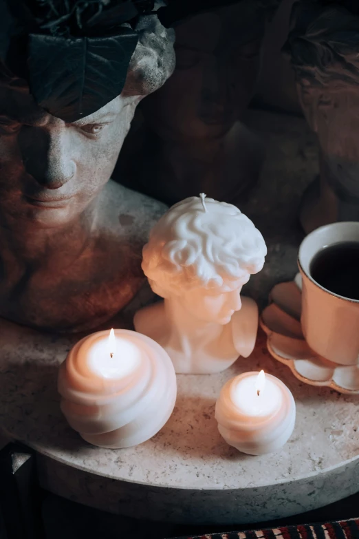 a white candle sits next to a cup of coffee