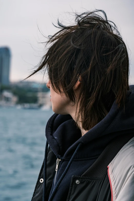 a guy wearing ear buds and jacket facing water