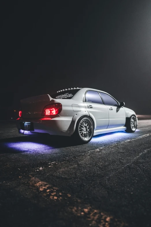 a white car that is sitting on the ground at night