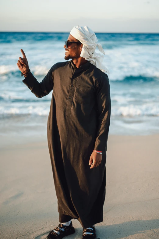 a man dressed in brown standing on a beach