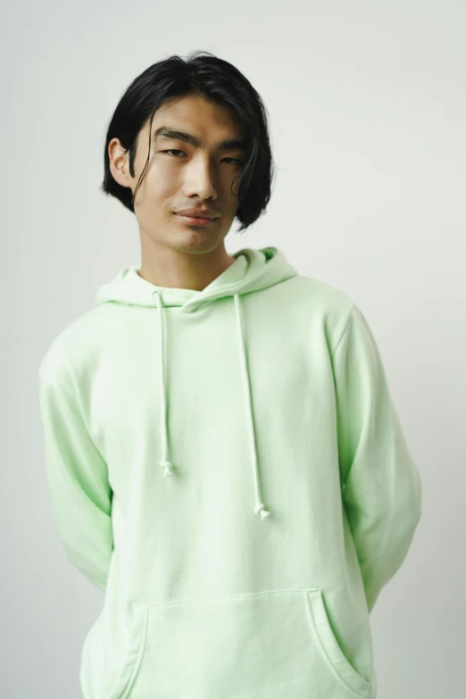 young man in green sweater standing against wall