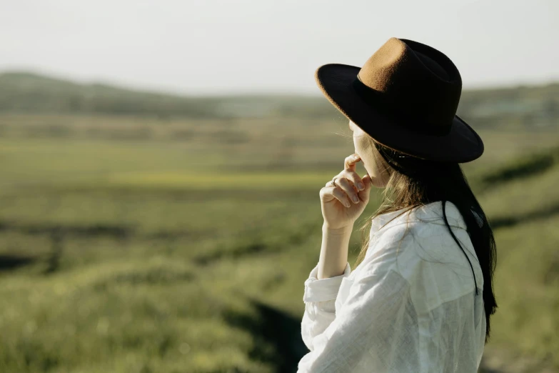 a woman with long hair and white shirt in front of a green grassy field