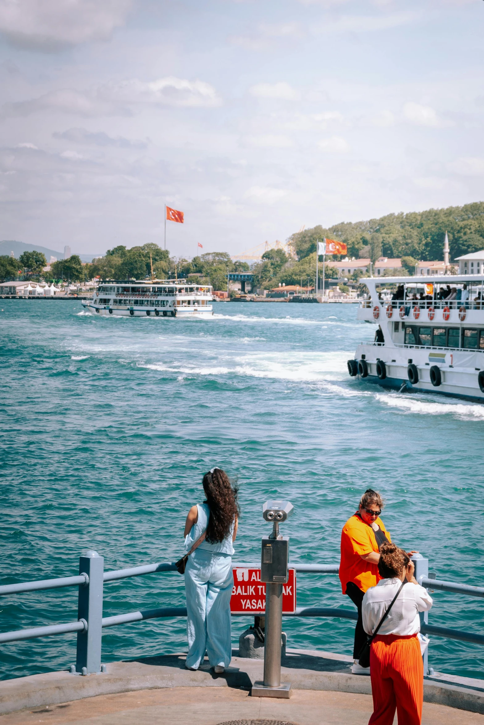 several people standing on a pier looking at some boats