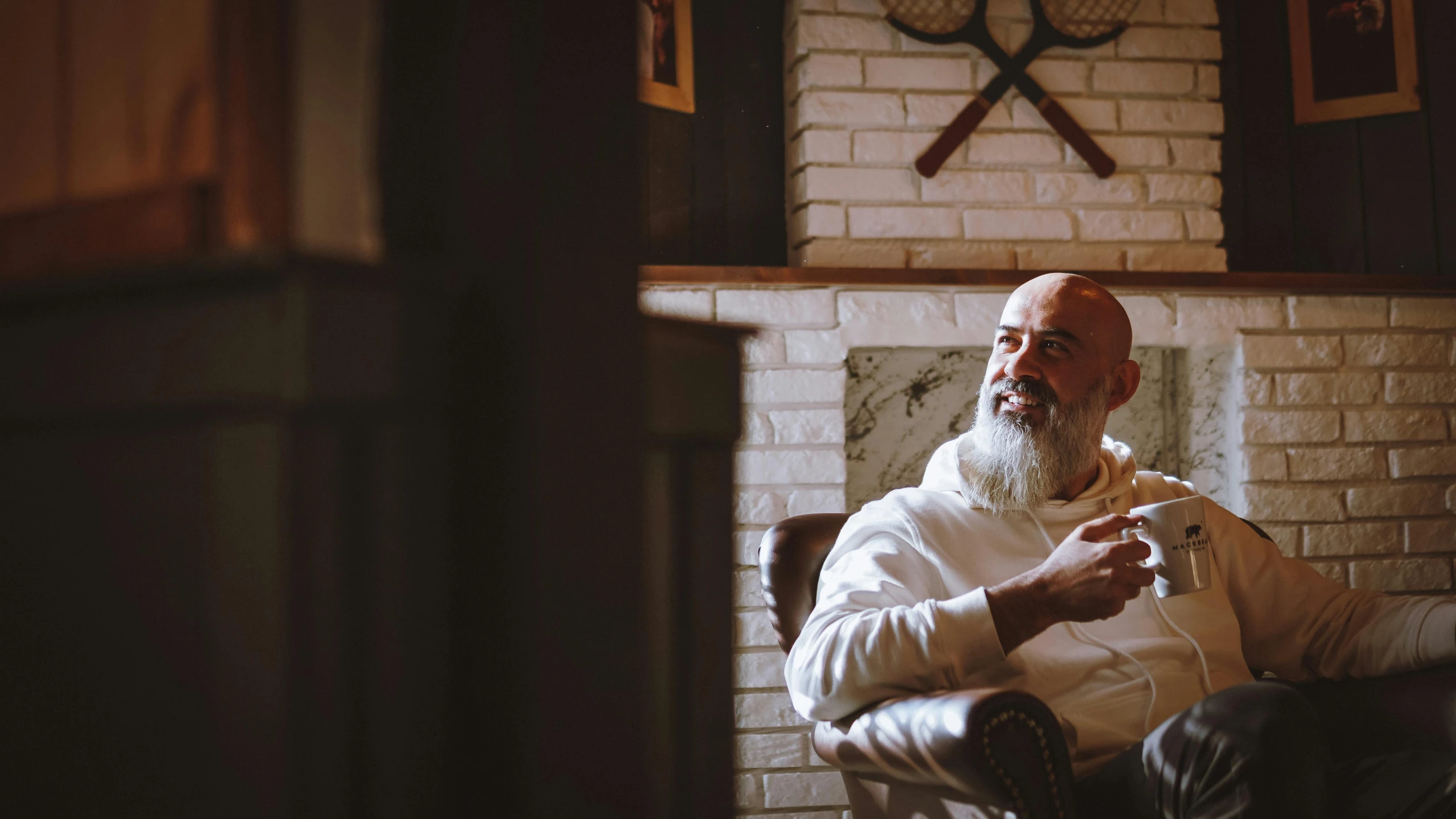 a man in white sitting in a chair with a cellphone