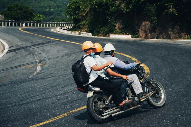 two people riding a motorcycle down the road