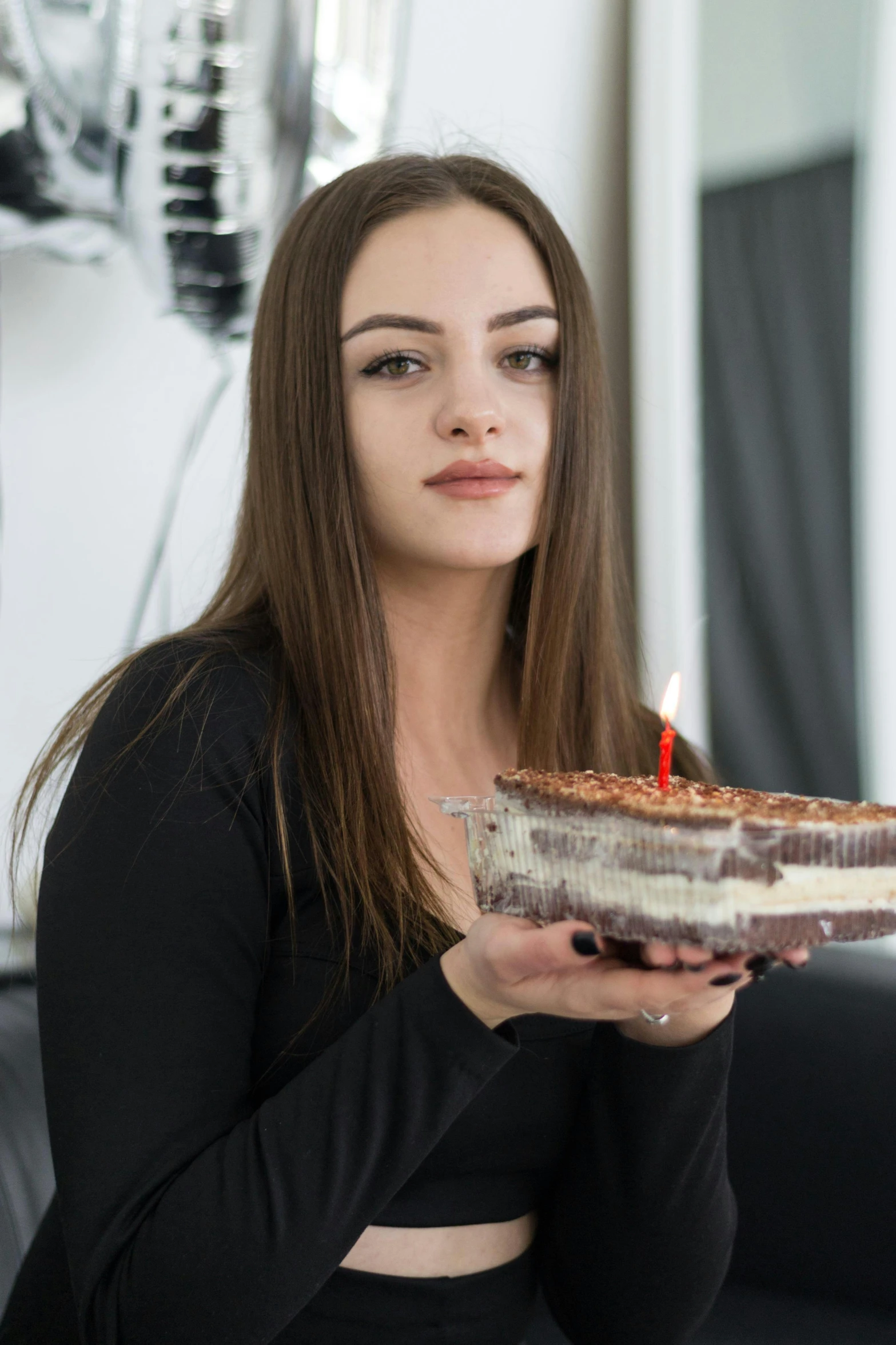a woman holding a chocolate cake with a lit candle