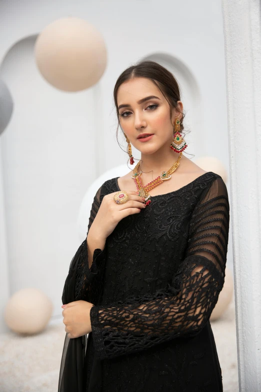 a woman in black dress standing near a wall