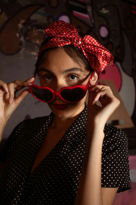 a woman in black and white dots with red sunglasses on