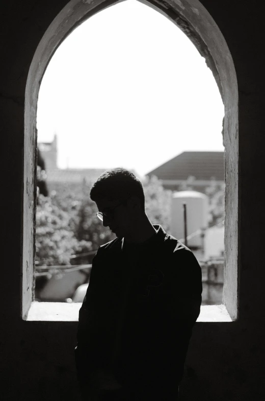 a man looking out an arched window at the city