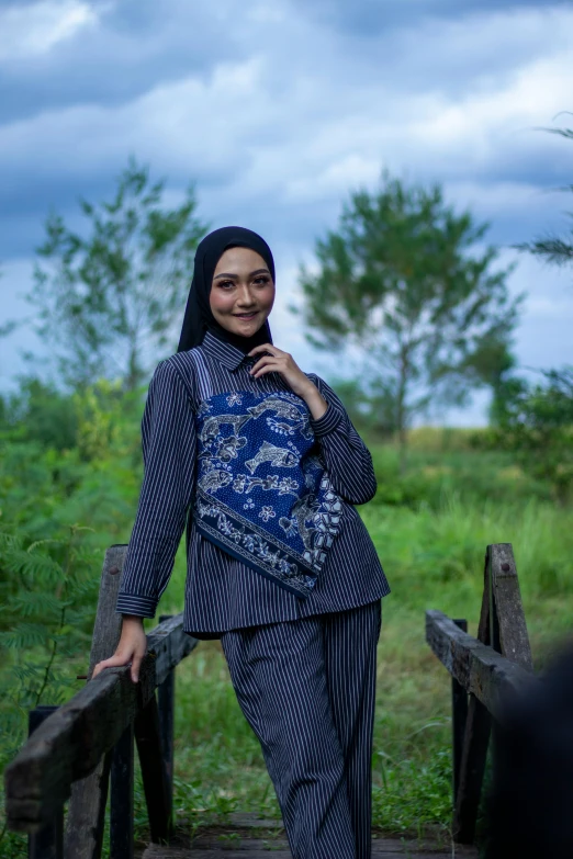 a woman standing on a bridge next to a green forest