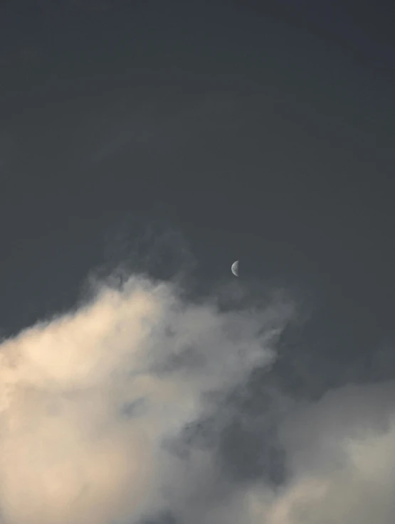 clouds are gathering in front of a half moon