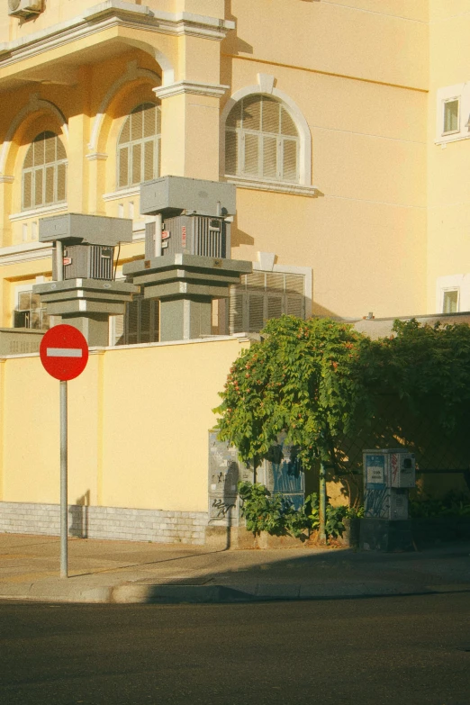 a tall yellow building next to a small red street sign