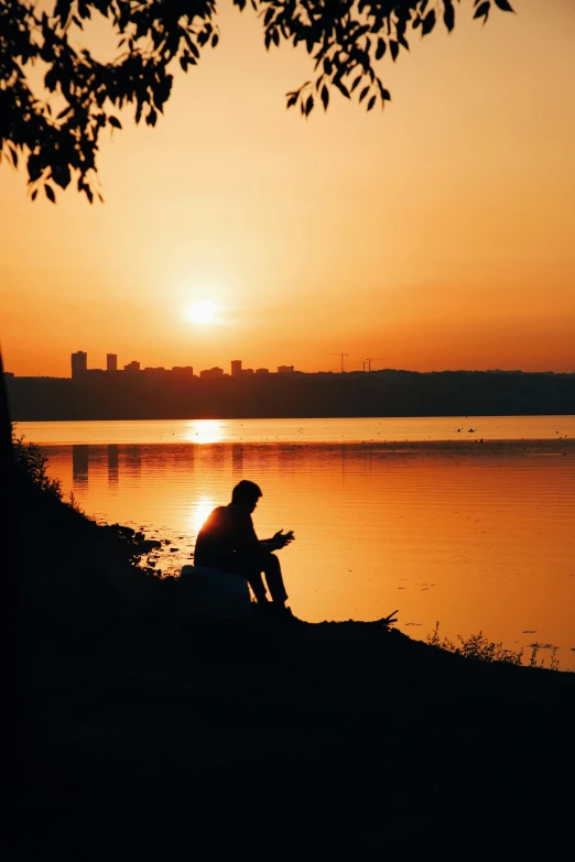 a man is sitting down while the sun sets