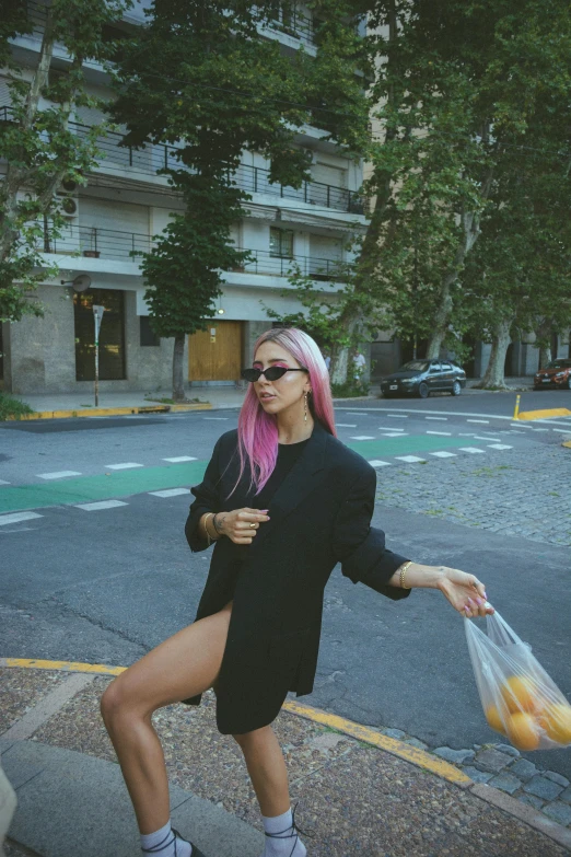 a woman with pink hair walking down a street