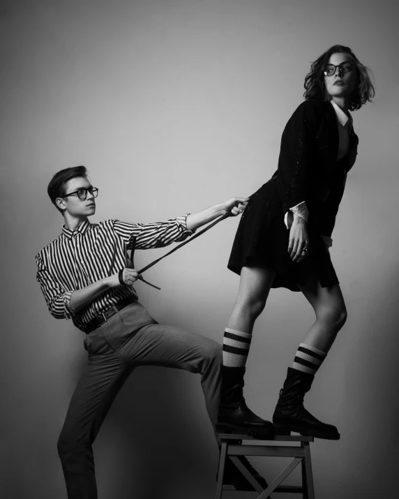 a man standing on top of a stool while holding the strings for a lady on the other side