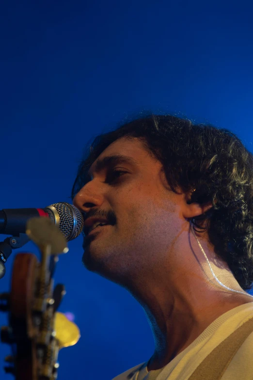 a man with a guitar on stage holding up a microphone