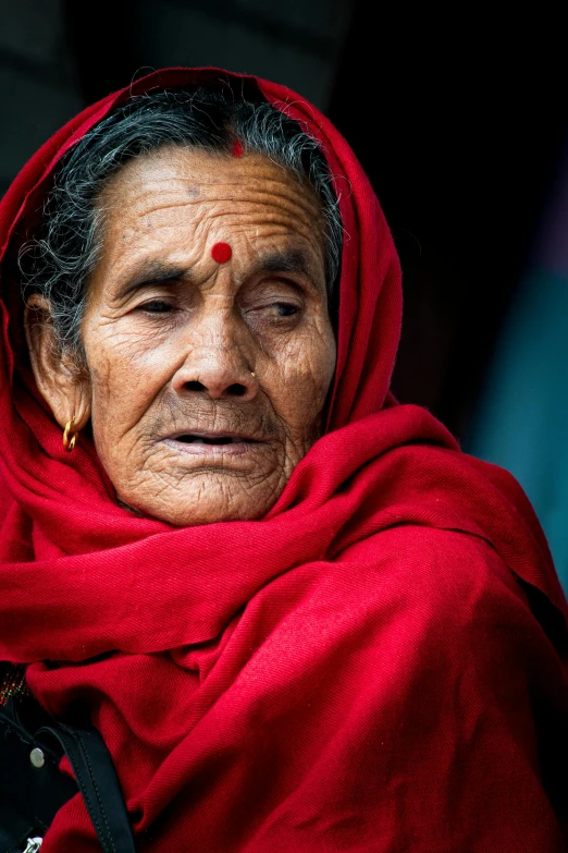 an old woman in a red scarf looking over her shoulder