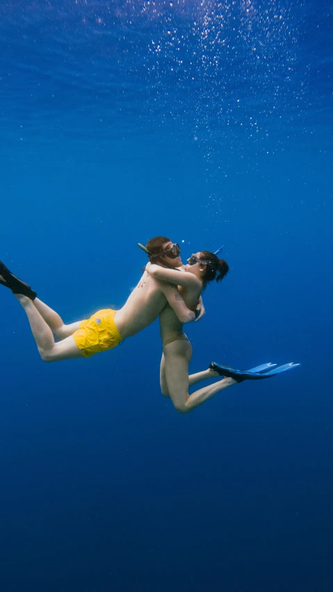 a woman in yellow swimsuit and a black flippers dives under water