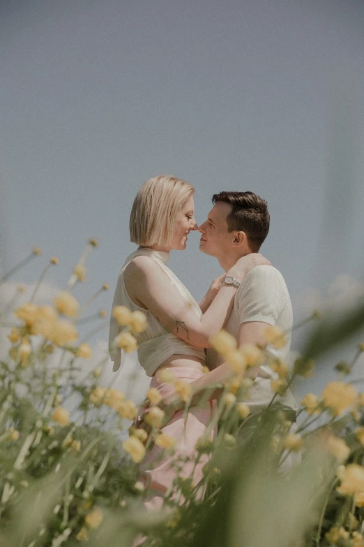 two people that are touching each other while standing in some flowers