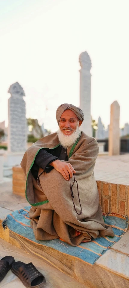 an old man is sitting on the ground next to some shoes