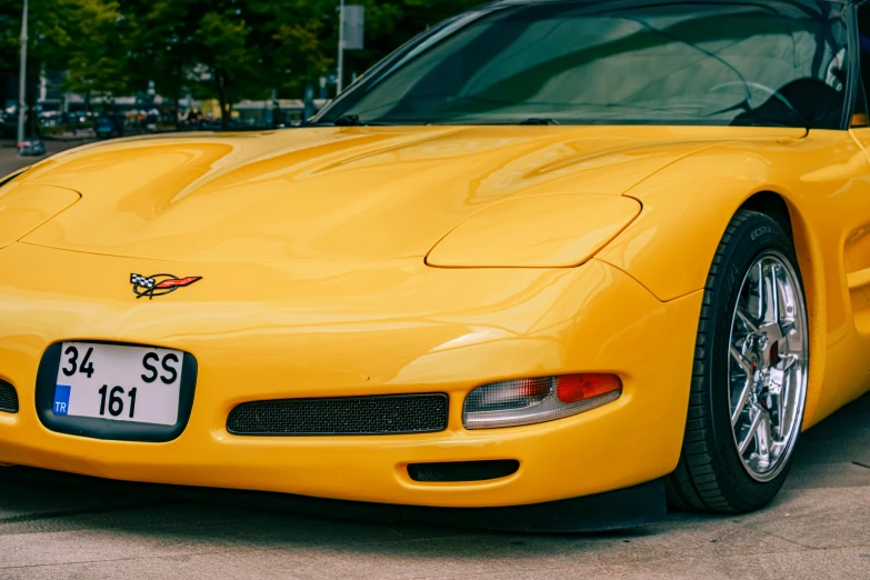 the front of a yellow sports car that is parked on the street