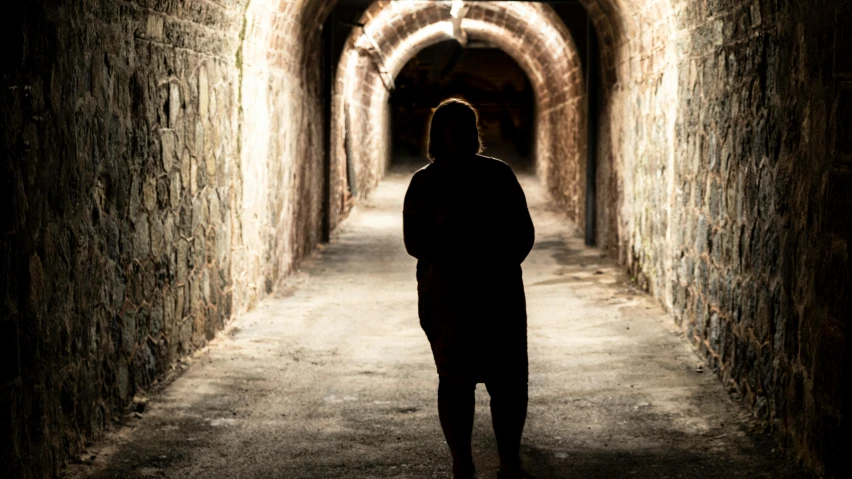 a man walks down an old fashioned tunnel