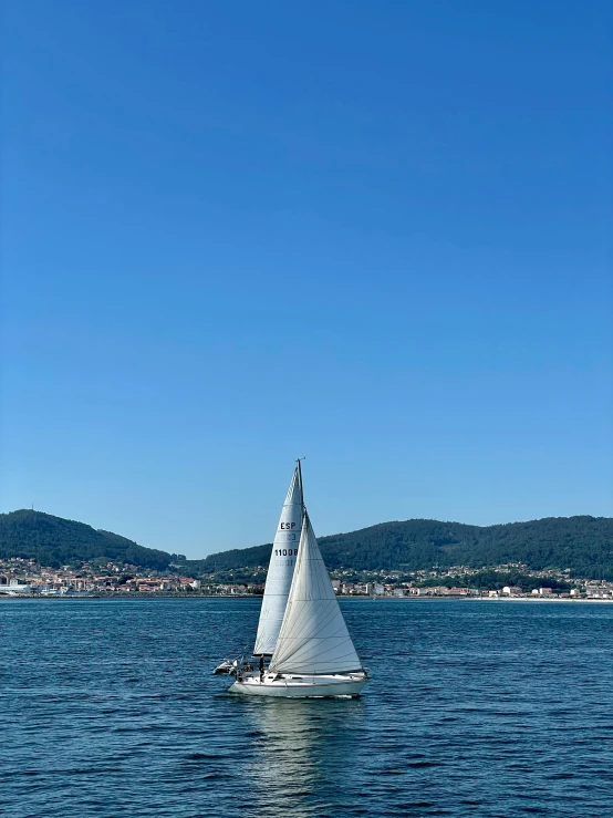 a sailboat on the water with mountains in the background