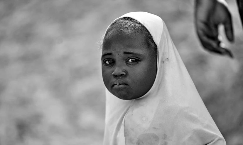 a woman in hijab with one hand holding onto her head