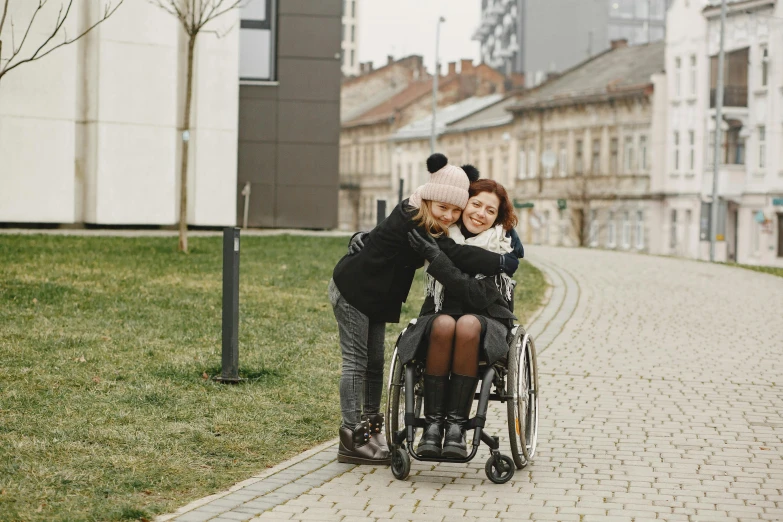 two women hugging and sitting in a wheelchair