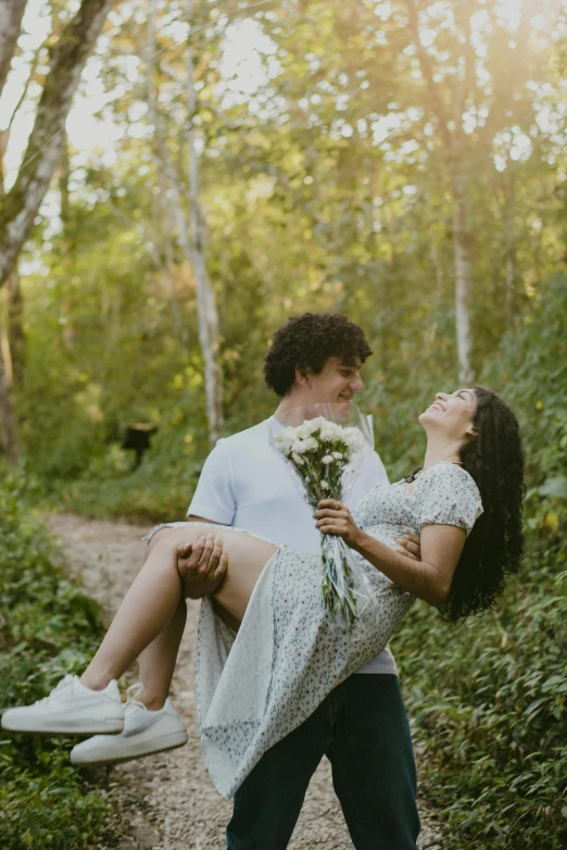 a young man carrying a woman in his arms in the woods