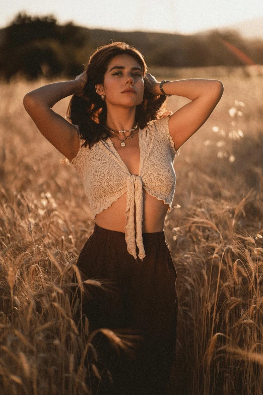 a woman wearing wide leg pants, standing in the middle of an open field