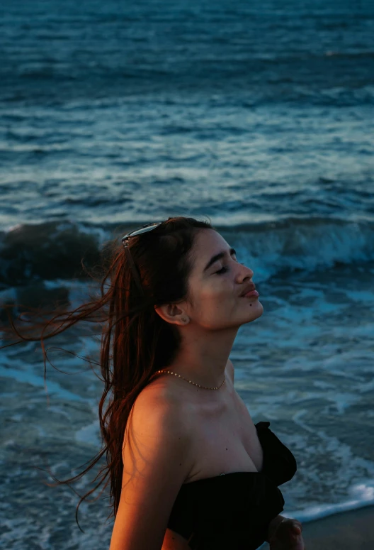 a woman in a black dress standing on the beach