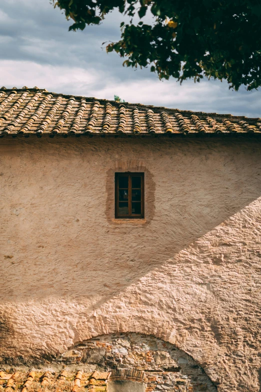 an old white building with stone wall and brown roof