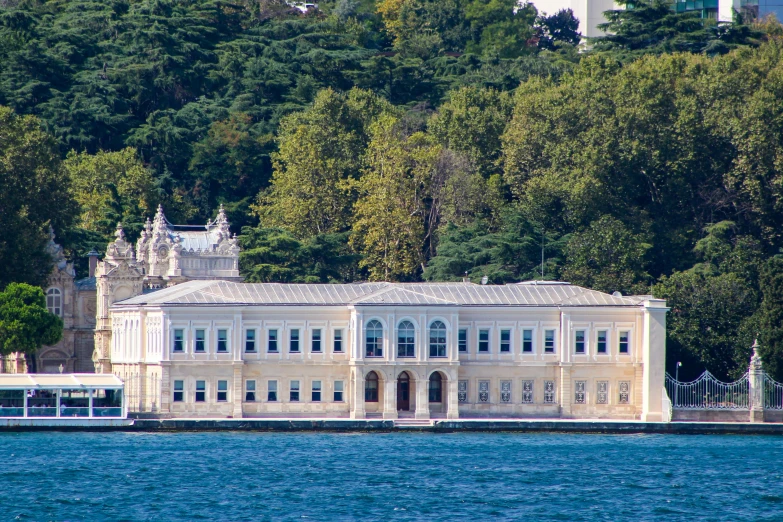 an ornate building stands on a hill side by the water