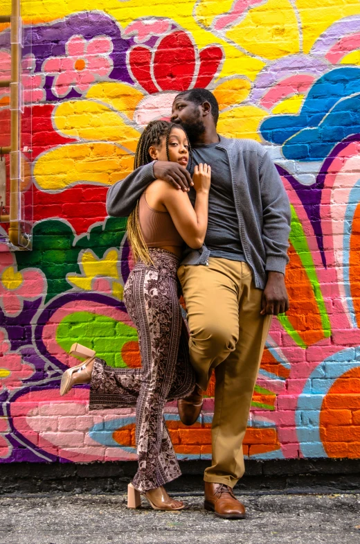 a man and woman emcing by a graffiti wall