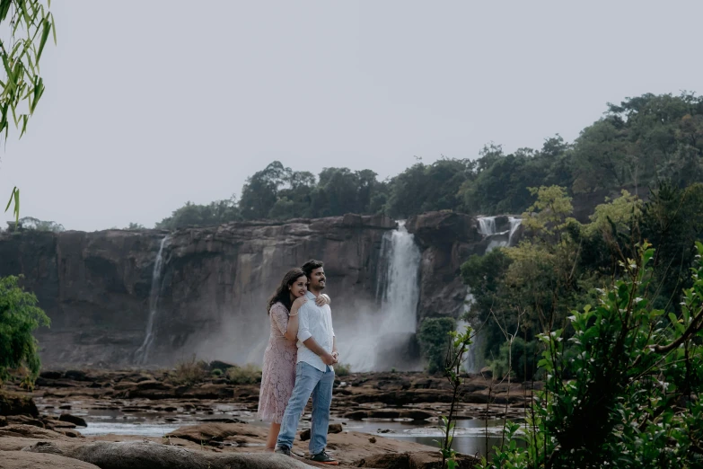 a young couple posing in front of a waterfall