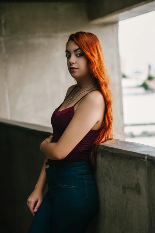 a woman standing next to the wall with red hair