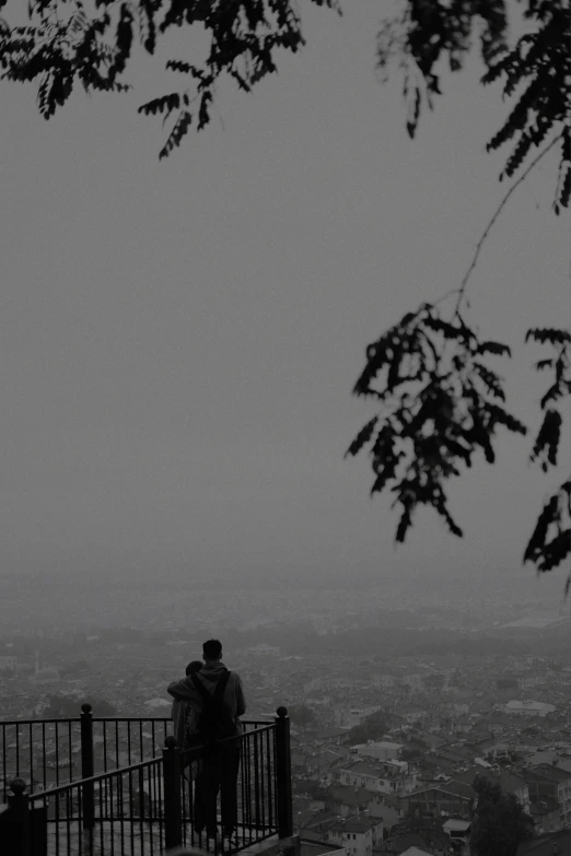 two people looking out at an city in the fog