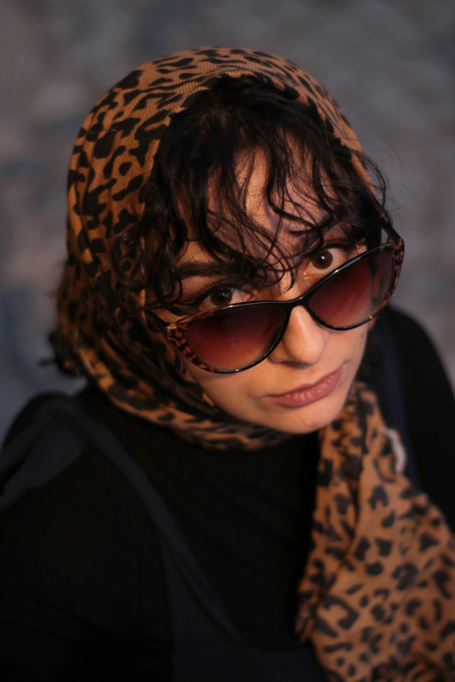 a woman wearing glasses with a leopard print scarf over her head