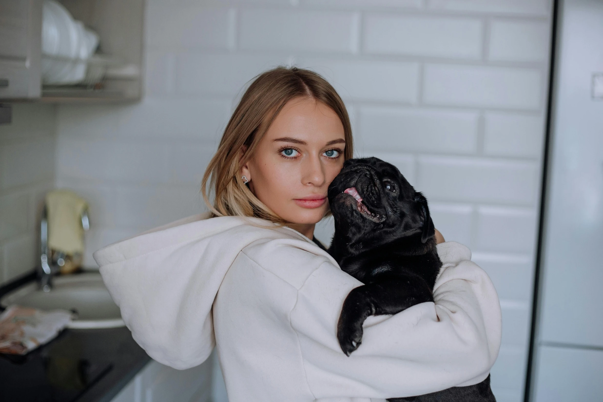 a woman in a bathrobe holding a dog in her arms