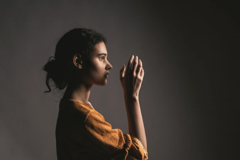 a woman is holding her hands together and standing