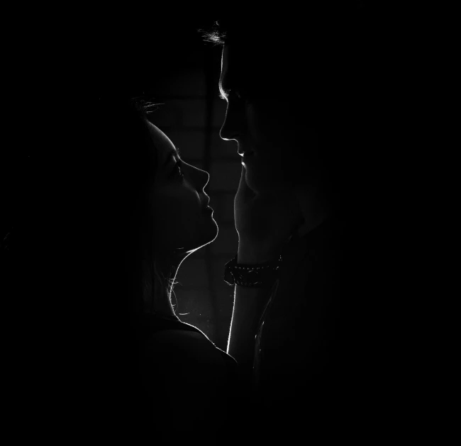 a silhouette of a man kissing his women head