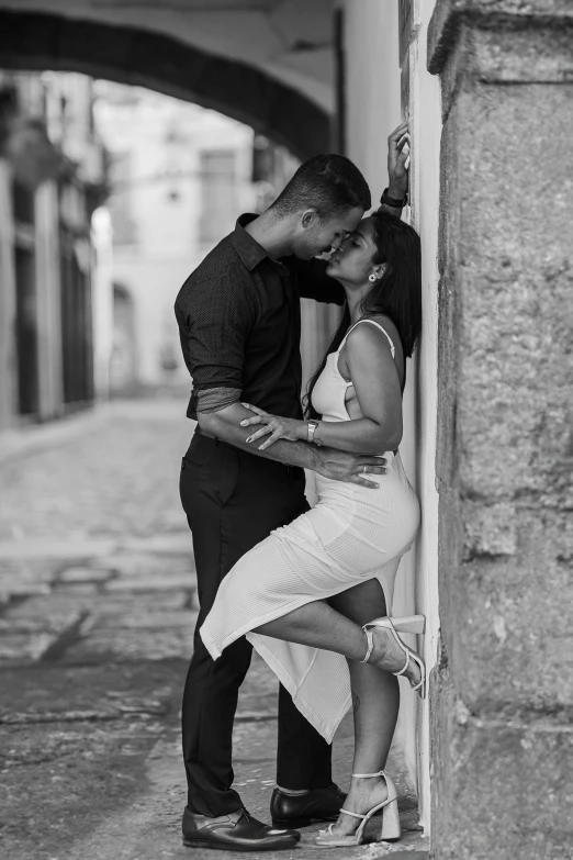 an engaged couple leaning up against the wall