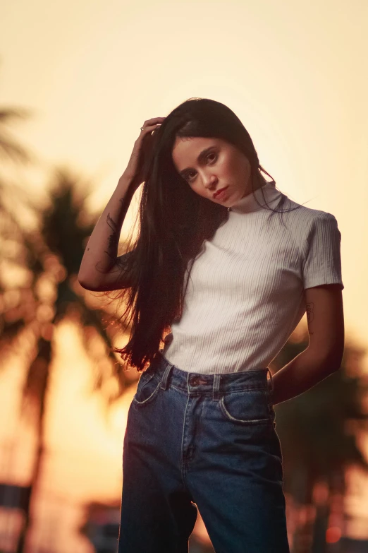 a beautiful young woman standing next to a palm tree