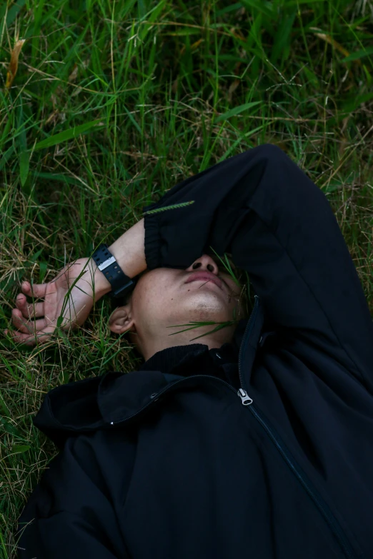 a man lays in the grass while wearing his watch
