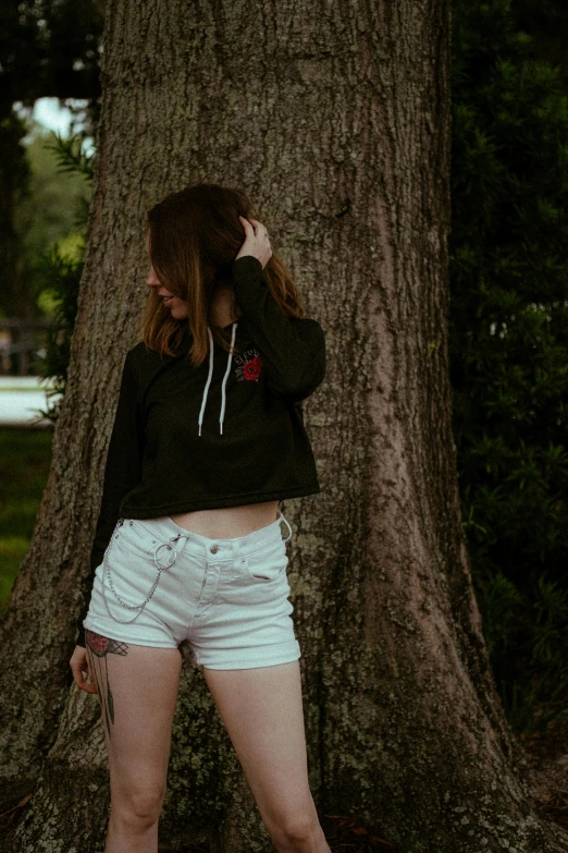 a woman in shorts standing next to a tree