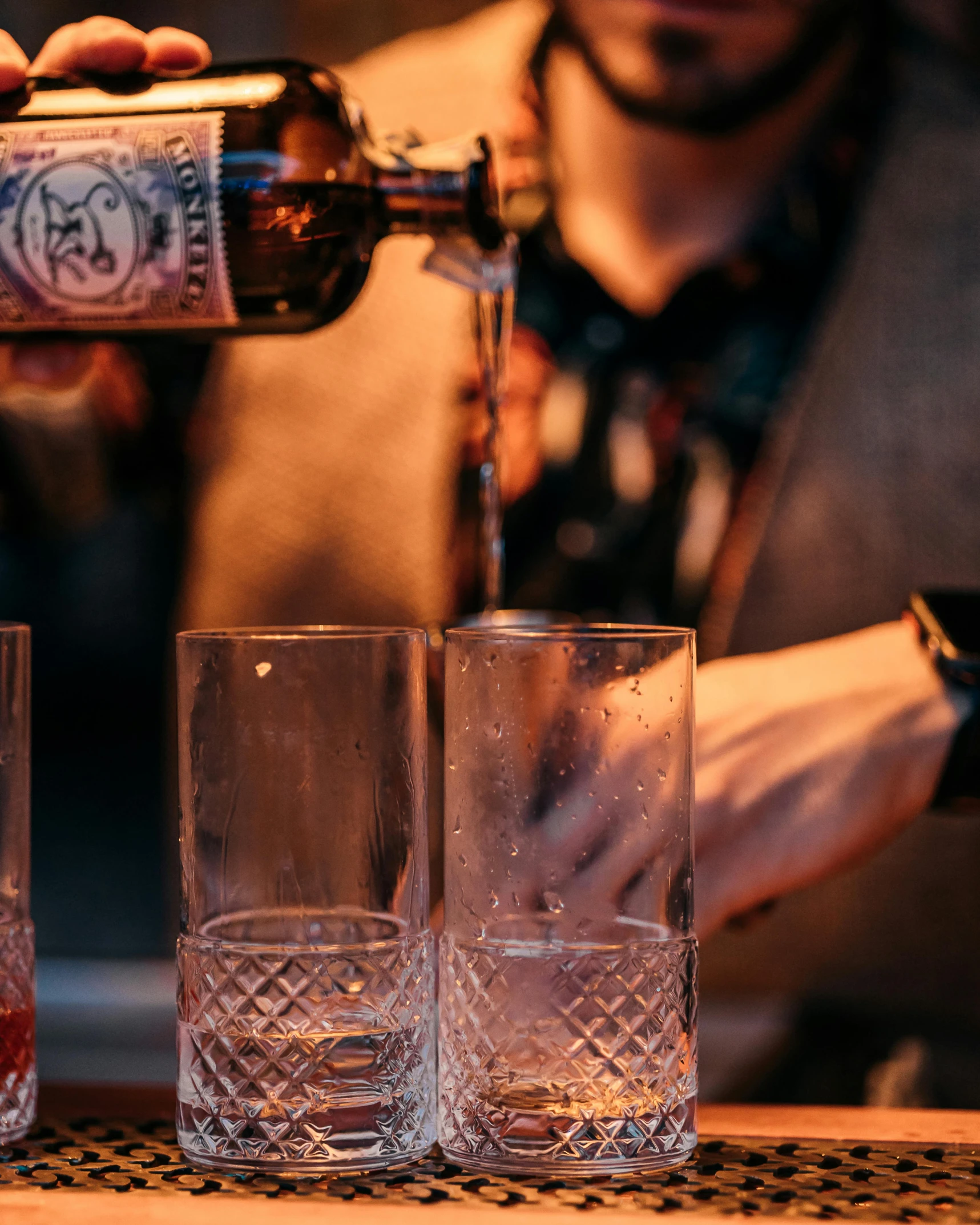 man pouring alcoholic drink from an old fashioned mixer